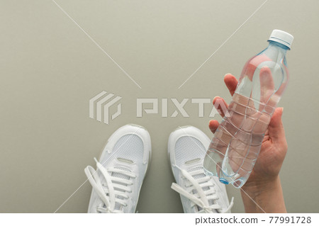 Female hand with a bottle of water in the gym Female hand with a bottle of water in the gym 77991728