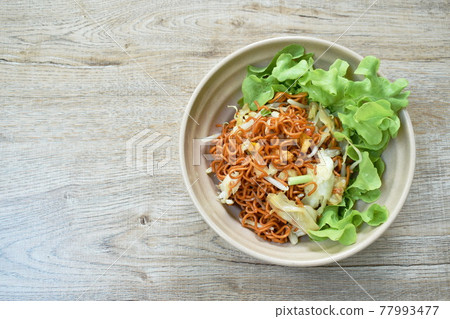 fried instant noodles with cabbage and egg in soybean sauce on bowl 77993477