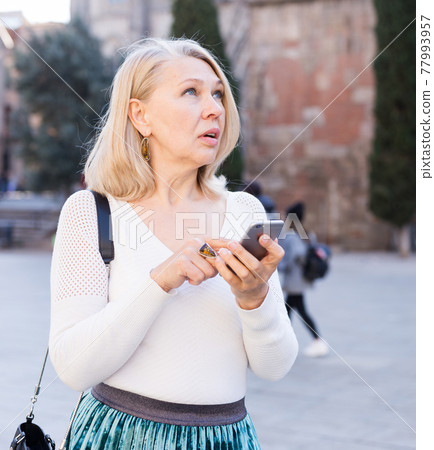 Elegant woman in white blouse makes selfie on smartphone Elegant woman in white blouse makes selfie on smartphone 77993957