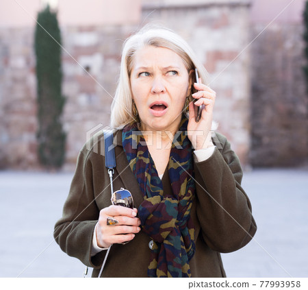 Angry woman is talking by phone on the street Angry woman is talking by phone on the street 77993958