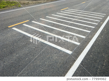 White transverse rumble strips on the asphalt road. White transverse rumble strips on the asphalt road. 77994982