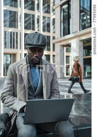 Man using laptop in the city Man using laptop in the city 77995098