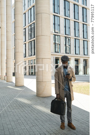 Businessman using phone outdoors 77995117