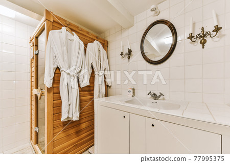 Cozy shower room with robes on hangers Cozy shower room with robes on hangers 77995375