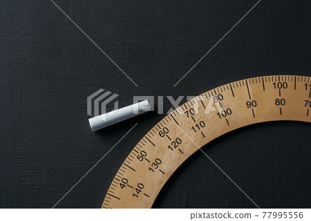 piece of chalk and protractor on a chalkboard piece of chalk and protractor on a chalkboard 77995556