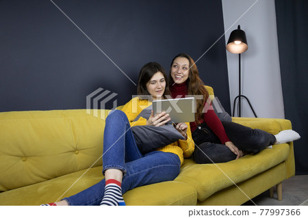two pretty long-haired brunette girls make purchases or payments online 77997366