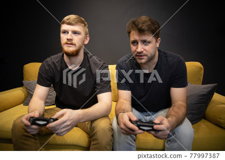 two cheerful handsome guys play passionately video game holding console gamepad two cheerful handsome guys play passionately video game holding console gamepad 77997387