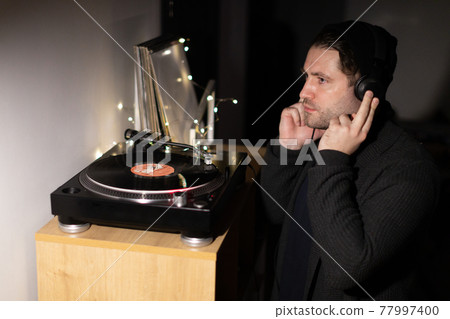 Young unshaven handsome millennial guy focused on music with headphones 77997400