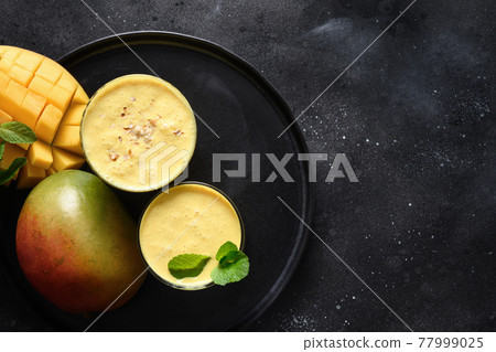Indian mango or turmeric lassi on black background 77999025