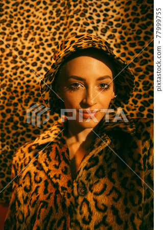 Woman wearing total leopard look looking at the camera with light smile Woman wearing total leopard look looking at the camera with light smile 77999755
