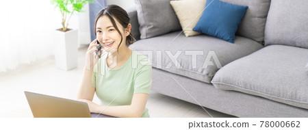 一位女士在家遠程辦公時撥打她的智能手機 78000662