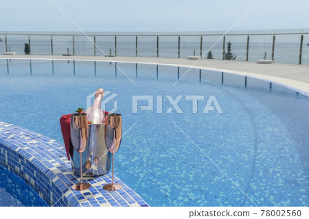 Bucket with champagne on the pool side Bucket with champagne on the pool side 78002560
