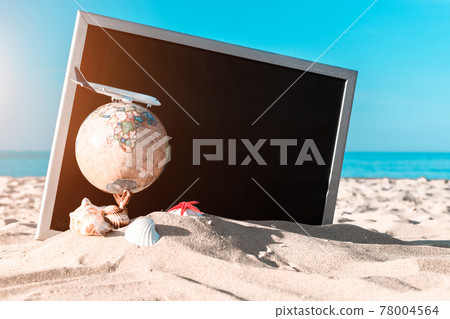 Sea shells. Starfish, seashells, toy plane and globe near blackboard on ocean nature beach. Tranquil beach scene with copy space. Sea shells. Starfish, seashells, toy plane and globe near blackboard on ocean nature beach. Tranquil beach scene with copy space. 78004564