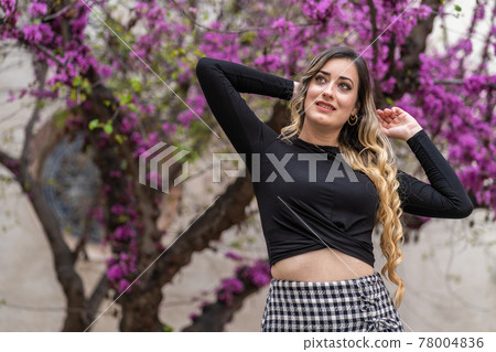 young happy woman in front of beautiful purple flowers 78004836