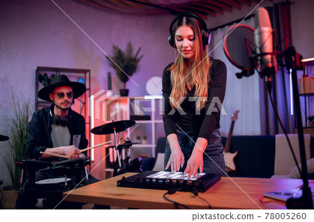 Man playing drums while woman mixing sounds on equalizer Man playing drums while woman mixing sounds on equalizer 78005260