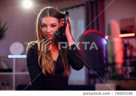 Singer in headphones standing in studio near microphone 78005286