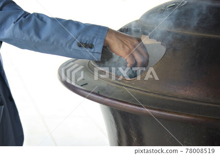 "Men's hand (release) to put incense sticks in the incense burner" 78008519