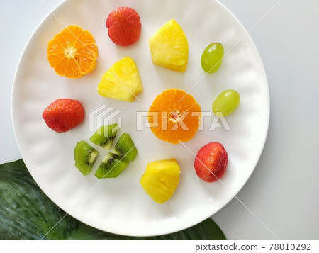 我把各種切好的水果放在一個白盤子裡。 78010292