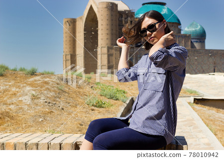 Beautiful young asian woman tourist in front of Mausoleum of Khoja Ahmed Yasawi. Central asia silk road tour. Beautiful young asian woman tourist in front of Mausoleum of Khoja Ahmed Yasawi. Central asia silk road tour. 78010942