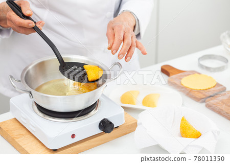 Senior woman frying a traditional dish from el Valle del Cauca in Colombia called empanada Senior woman frying a traditional dish from el Valle del Cauca in Colombia called empanada 78011350