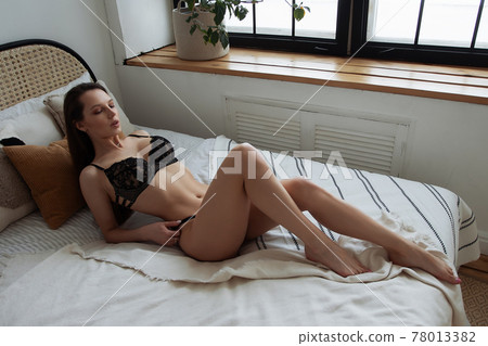 Alluring brunette in black lingerie on bed Alluring brunette in black lingerie on bed 78013382