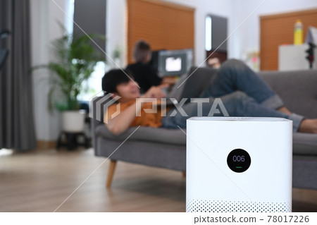 Air purifier in living room and young man resting on sofa. 78017226