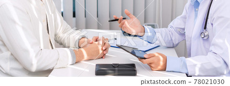 Medical concept a smart male doctor wearing a mask consulting with patient about how to recover from Coronavirus outbreak (COVID-19) at his modern clinic 78021030