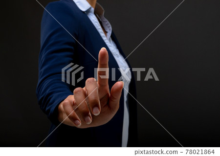 Mid section of businesswoman touching touching invisible screen against black background Mid section of businesswoman touching touching invisible screen against black background 78021864