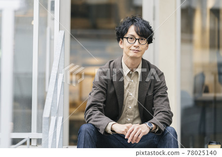 Portrait of a man in his thirties wearing smiling glasses looking at the camera 78025140