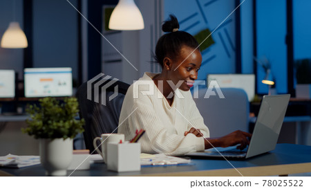 Happy african freelancer reading tasks on laptop working overtime Happy african freelancer reading tasks on laptop working overtime 78025522