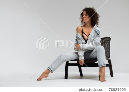 Stylish curly haired woman in denim outfit 78025603