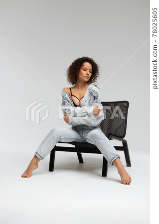 Stylish curly haired woman in denim outfit 78025605