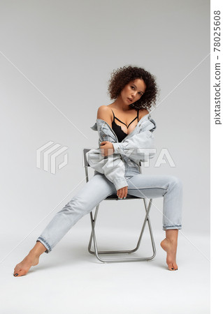 Stylish curly haired woman in denim outfit 78025608