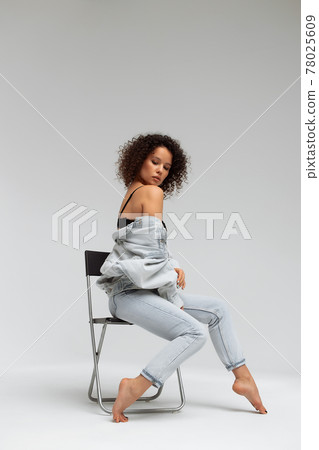 Stylish curly haired woman in denim outfit 78025609