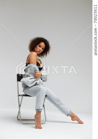 Stylish curly haired woman in denim outfit 78025611