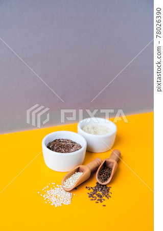 Wooden spoons with flax and sesame seeds lies in a white mortar on a yellow background. Healthy eating. Keto diet. Minimalistic concept in isometric style in trendy colors 78026390