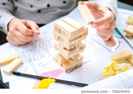 Architect designer Interior creative working hand playing a block wood game on desk architectural plan of the house, a color palette. Female architect drawing blueprints in office workplace. 78026403