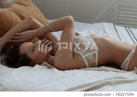 Alluring brunette in white lingerie on bed Alluring brunette in white lingerie on bed 78027594