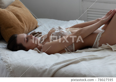Alluring brunette in white lingerie on bed Alluring brunette in white lingerie on bed 78027595