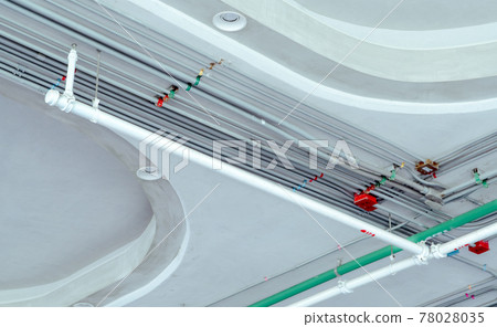 Electrical conduit system and galvanized steel pipe of electric cable installed on ceiling. Automatic fire sprinkler safety system with white pipe. Building construction. Fire protection and detector. 78028035