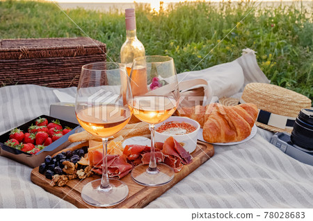 Picnic with strawberries, croissants and appetizers on the board and rose wine. 78028683