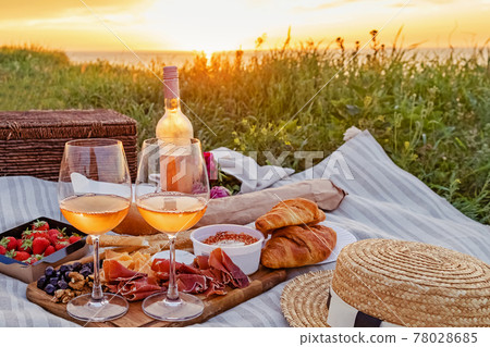 Picnic with strawberries, croissants and appetizers on the board and rose wine. 78028685
