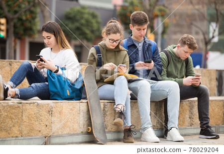 Teenagers are playing on smartphone on street Teenagers are playing on smartphone on street 78029204