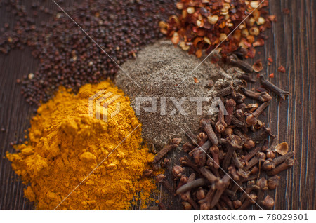Sorted spices on dark wood background, seasonings for food. Top view of curry, paprika, pepper, cloves, bay leaf, turmeric, spices concept. 78029301