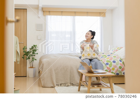 坐在床上，看著她的智能手機的年輕女人 78030246