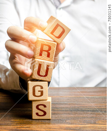 Man breaks tower blocks with word Drugs. Combating the illicit manufacture and distribution of dangerous drug chemicals. Prevention, information campaign. Addiction rehabilitation. Stop doing drugs 78031145