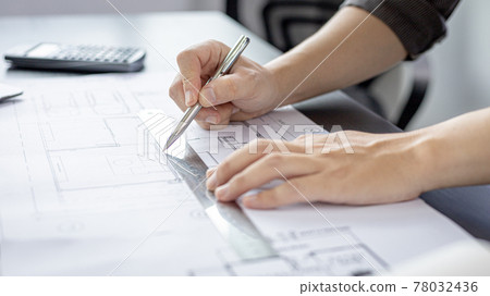 Engineer and Architect concept, Man uses a ruler to measure the floor plan on the blueprint, Building architecture design work, Construction design project under environmental conservation conditions. 78032436