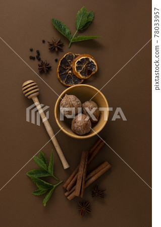 Condiments and spices, honey spoon, anise star, cinnamon sticks, mint leaves, brown background top view Condiments and spices, honey spoon, anise star, cinnamon sticks, mint leaves, brown background top view 78033957