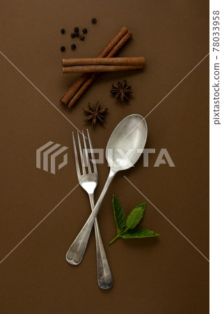 Food mock up. Fork and spoon with condiments - cinnamon sticks, anise star, mint leaves. Top view. Food mock up. Fork and spoon with condiments - cinnamon sticks, anise star, mint leaves. Top view. 78033958