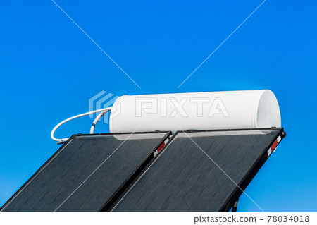 Solar water heater on the roof of a building against the background of the sky. Using solar energy to heat water Solar water heater on the roof of a building against the background of the sky. Using solar energy to heat water 78034018